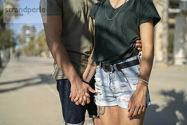 Young couple holding hands at beach on sunny day