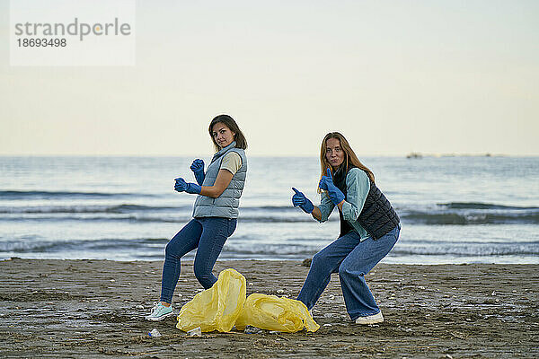 Umweltschützer tanzen an Plastiktüten am Strand vorbei