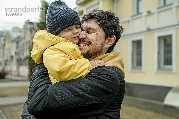 Happy father embracing son wearing knit hat