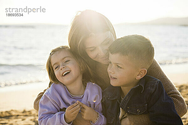 Lächelnde Frau mit Tochter und Sohn am Strand