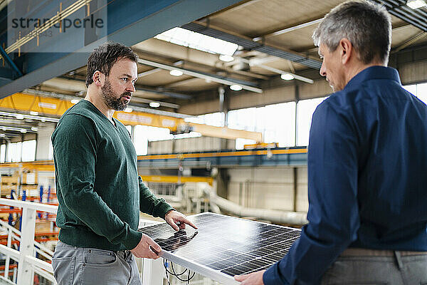 Manager diskutiert mit Geschäftsmann  der Solarpanel in der Fabrik hält