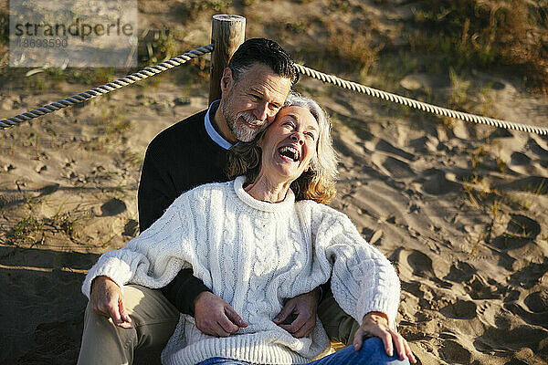 Happy woman enjoying with man sitting at beach