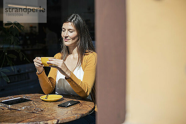 Frau hält Kaffeetasse am Tisch im Café