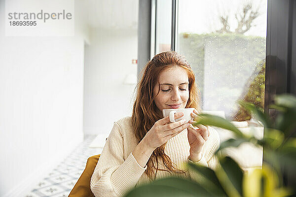 Lächelnde Frau riecht Kaffee im Hotel