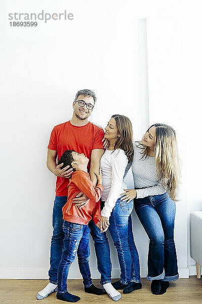 Glückliche Familie verbringt ihre Freizeit damit  zu Hause an der Wand zu stehen