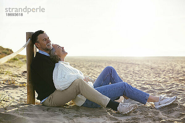 Lächelndes älteres Paar verbringt seine Freizeit im Sand am Strand