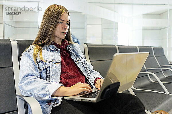 Junge Frau benutzt Laptop in der Flughafenlobby