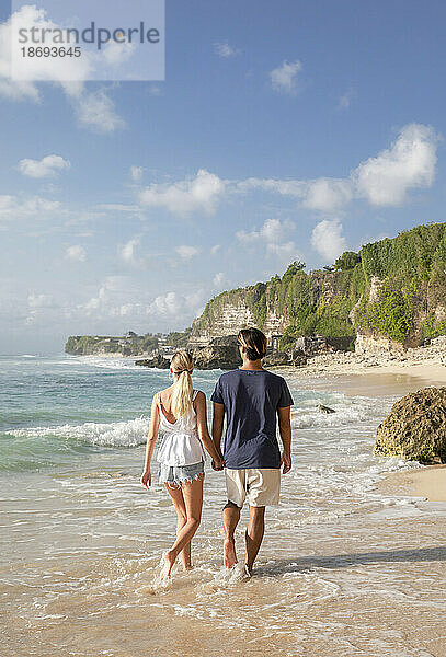 Paar hält Händchen und geht am Strand spazieren