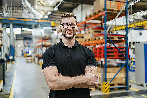 Lächelnder Mitarbeiter mit Brille in der Fabrik