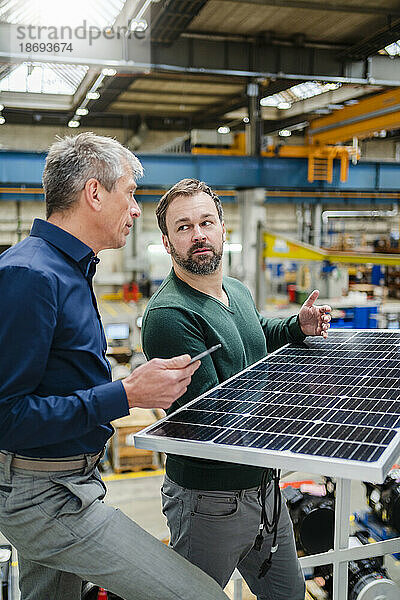 Reifer Manager diskutiert mit Geschäftsmann in der Fabrik über Solarpanel