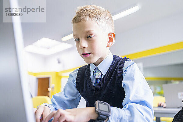 Konzentrierter Junge benutzt Laptop im Computerunterricht