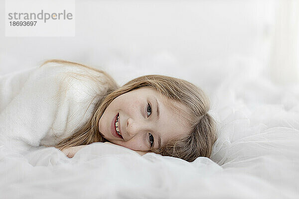 Smiling girl lying in front of wall