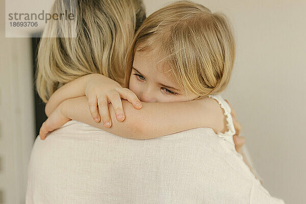 Traurige Tochter umarmt Mutter zu Hause