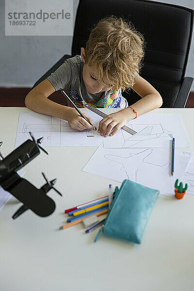 Junge zeichnet zu Hause mit Bleistift auf Papier