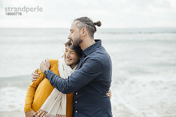 Reifer Mann umarmt Frau am Strand