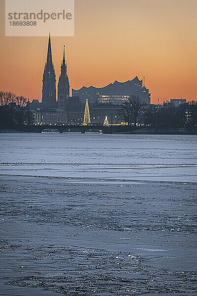 Deutschland  Hamburg  Eis schwimmt in der Abenddämmerung auf der Außenalster  im Hintergrund die Skyline der Stadt