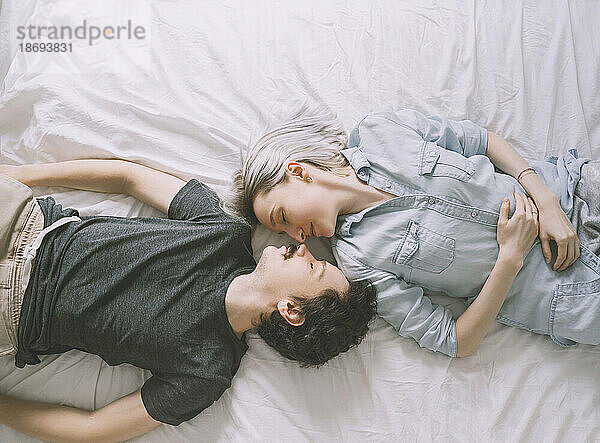 Loving couple lying on bed at home