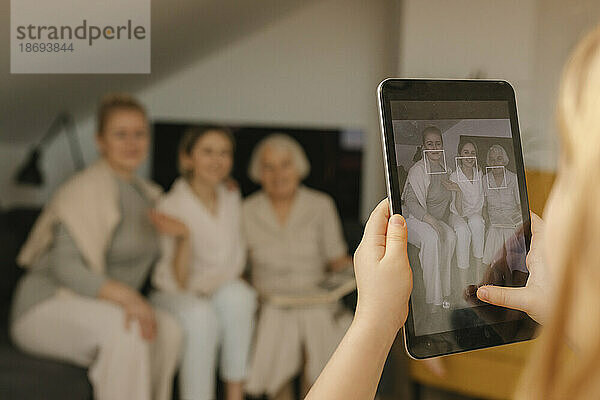 Mädchen fotografiert Familie zu Hause mit Tablet-PC