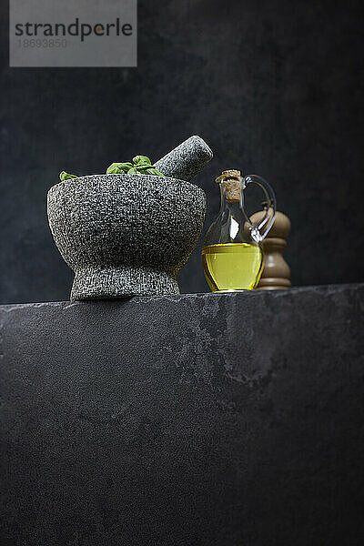 Studio shot of jug of olive oil and stone mortar