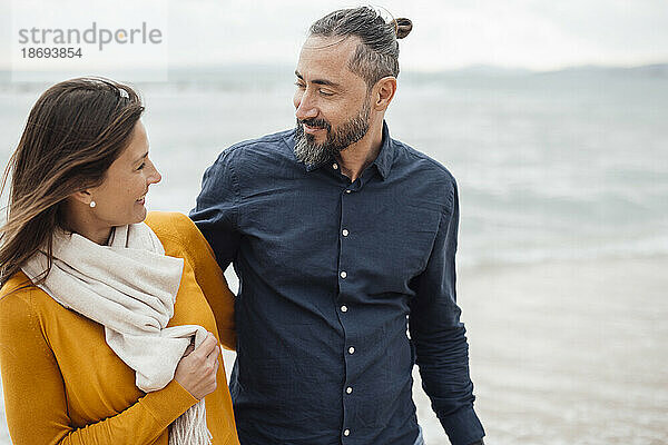 Glückliche Frau und Mann  die am Strand spazieren gehen