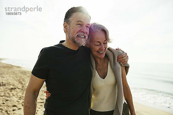 Glücklicher Mann mit Arm um Frau am Strand