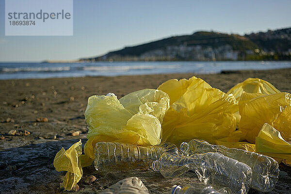 Am Strand verstreute Plastiktüten und Flaschen