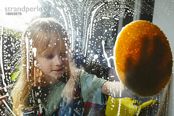 Rothaariges Mädchen putzt Fensterglas