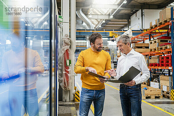 Lächelnde Geschäftskollegen planen in der Produktionshalle der Fabrik