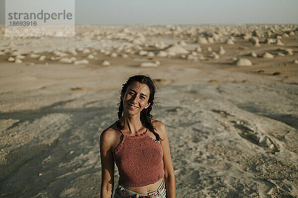 Lächelnde Frau  die an einem sonnigen Tag in der Wüste steht