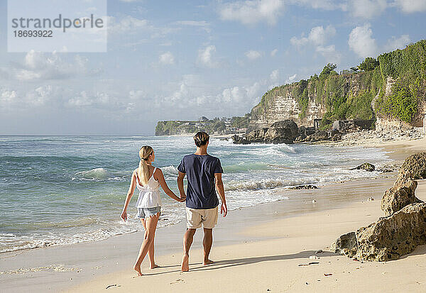 Junges Paar geht gemeinsam am Strand spazieren