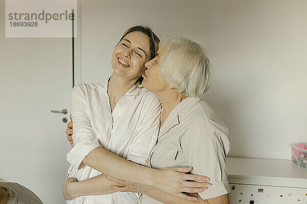 Ältere Frau küsst Enkelin zu Hause