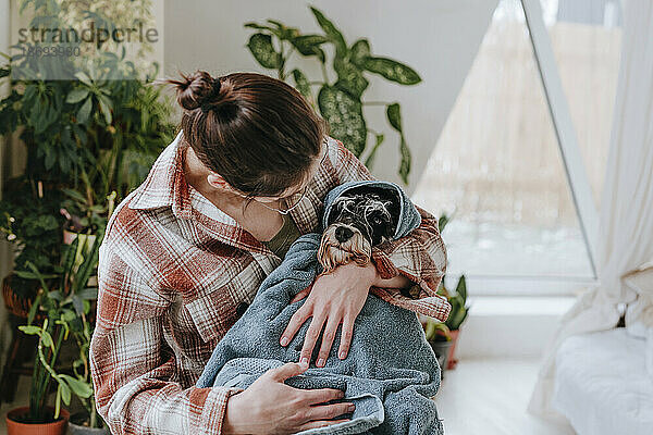 Frau umarmt Hund  in Handtuch gewickelt