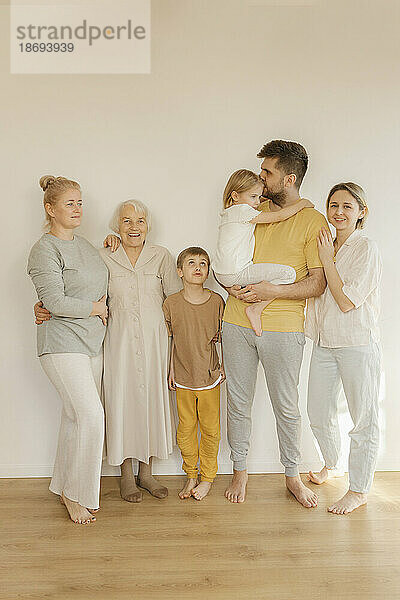 Glückliche Mehrgenerationenfamilie  die zu Hause gemeinsam vor der Wand steht