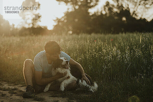 Man kissing border collie dog at field