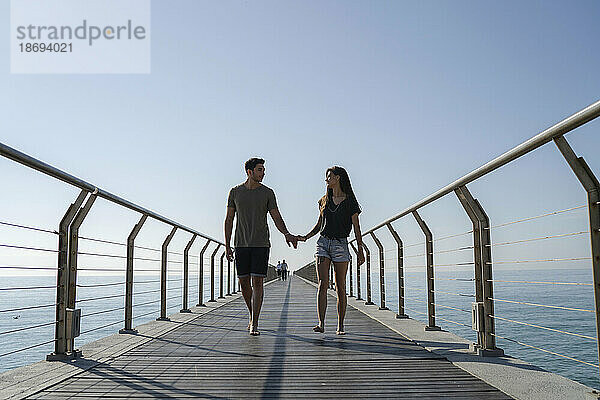 Junges Paar läuft auf Brücke unter freiem Himmel
