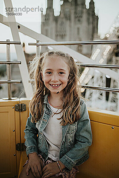 Lächelndes Mädchen sitzt im Riesenrad im Vergnügungspark