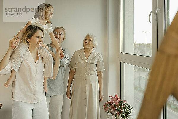 Familie genießt mit Enkelin am Fenster zu Hause