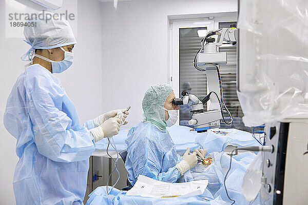 Krankenschwester mit Chirurg  der im Operationssaal eine Augenoperation durchführt