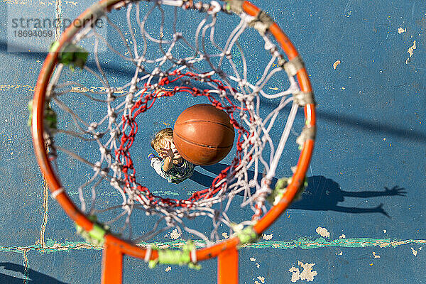 Son throwing basketball standing under hoop