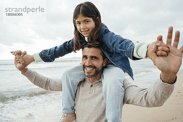 Glücklicher Mann trägt Tochter am Strand
