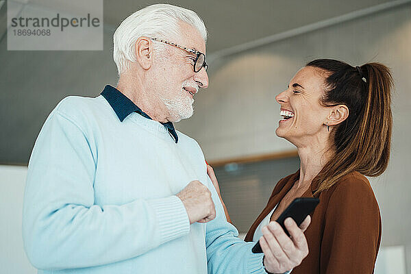 Lachende junge Frau und älterer Mann mit Smartphone