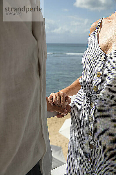 Junges Paar hält Händchen am Strand