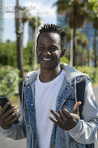 Lächelnder Mann gestikuliert mit Smartphone