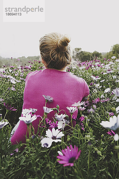 Frau mit Haarknoten inmitten bunter Gänseblümchen im Feld