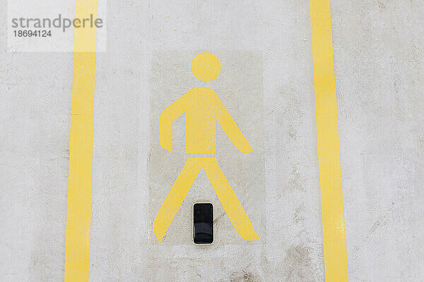 Smart phone below walking sign on floor in factory
