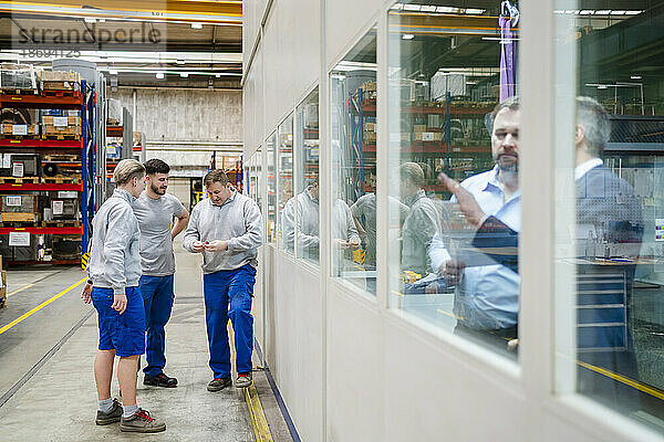 Kollegen reden miteinander und stehen in der Produktionshalle der Fabrik