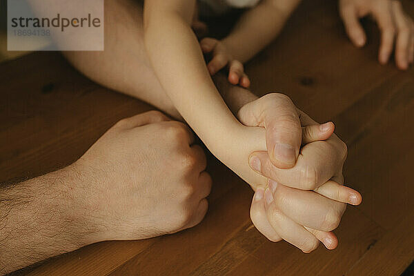 Father holding hand of daughter at table