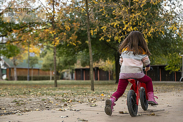 Mädchen fährt Fahrrad auf Fußweg im Park