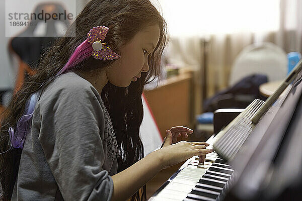 Mädchen mit langen Haaren lernt Klavier spielen