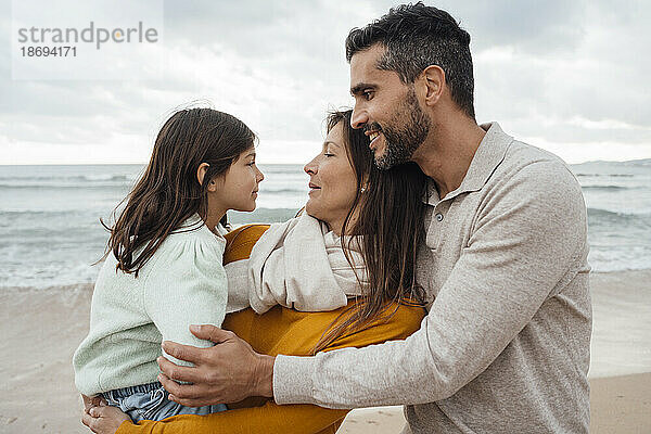 Lächelnder Mann und Frau mit Tochter am Strand